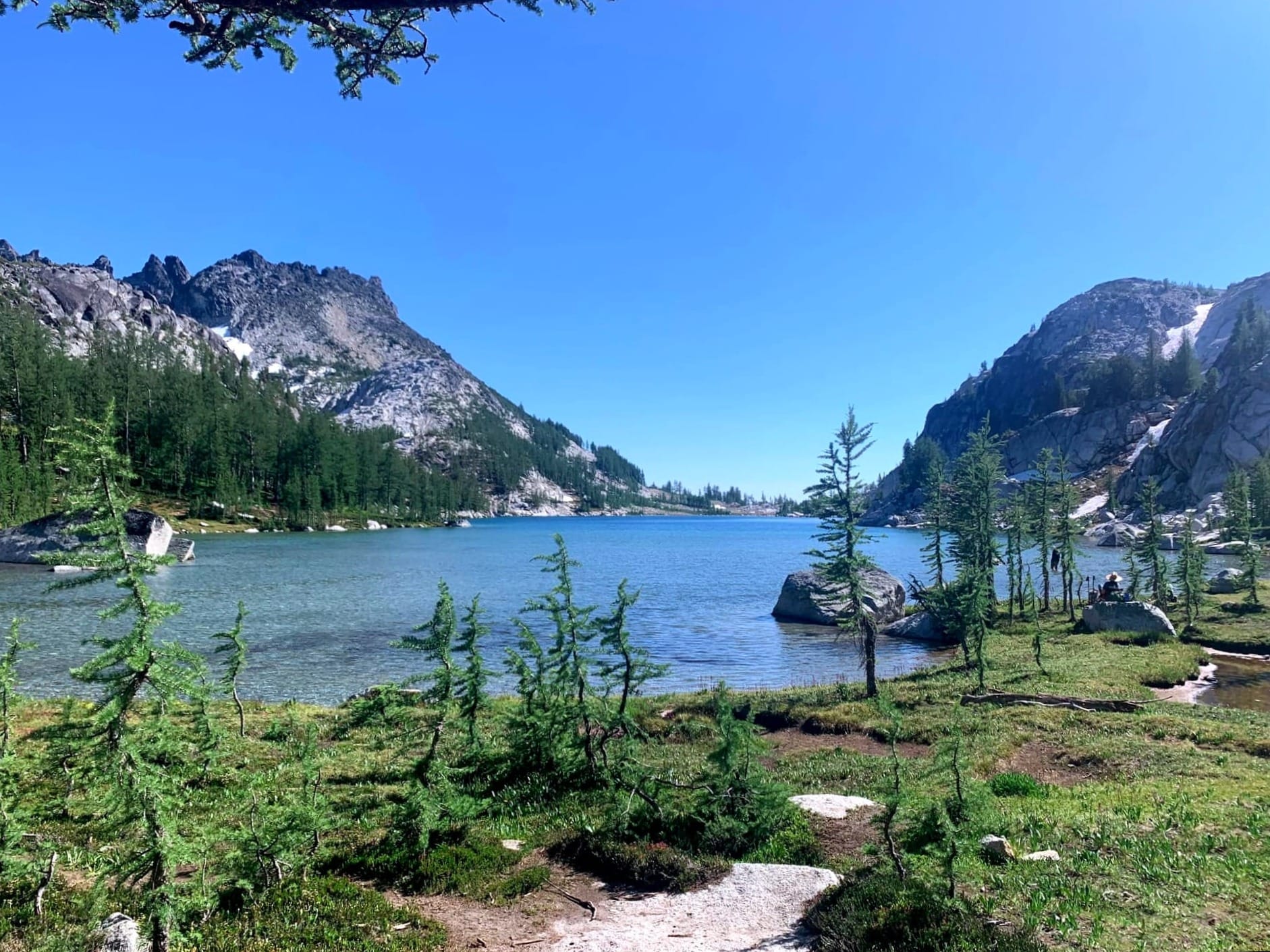 An alpine lake with various trees and mountains surrounding it in the Enchantments, Washington.